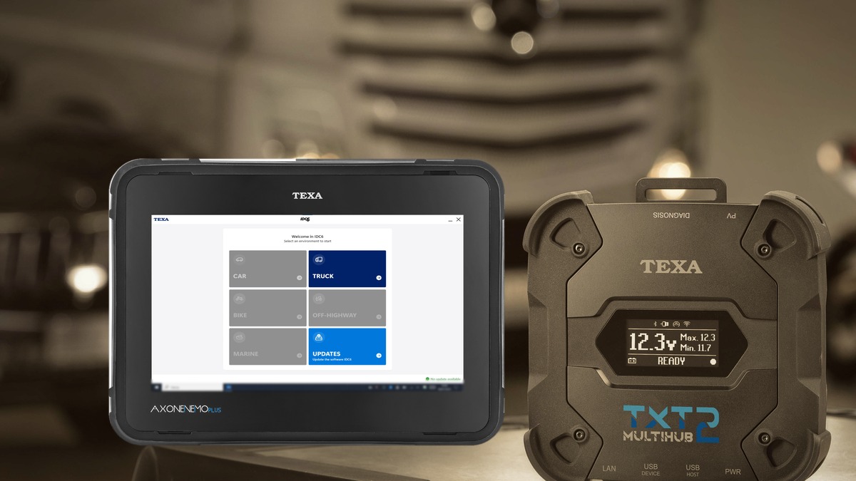 TEXA AXONE Nemo Plus tablet on the IDC6 home screen beside a TEXA TXT Multihub 2 with its display lit, on a shop workbench with a truck in the background.